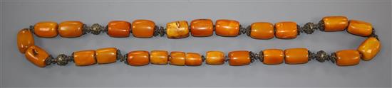 A Persian single strand barrel shaped amber bead and metal mounted necklace, gross weight 146 grams, 78cm.
